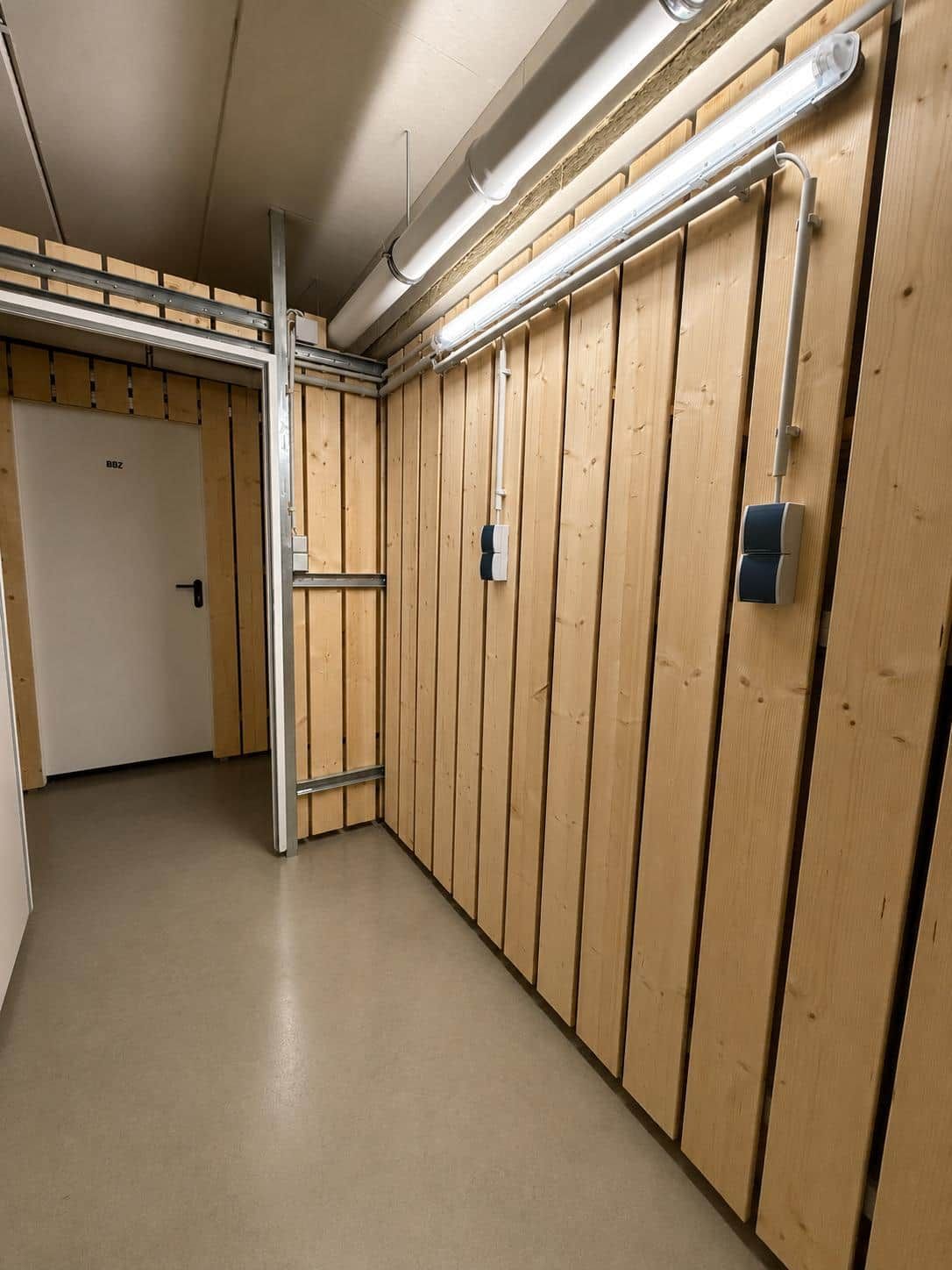 Una habitación con paneles de madera, una puerta y una escalera de metal.