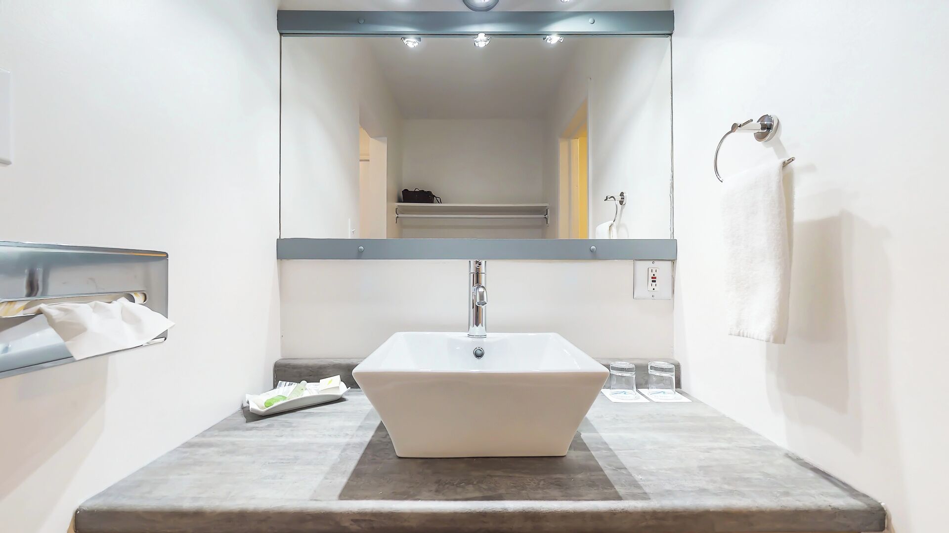 A bathroom with a white sink, a towel rack, and a mirror.