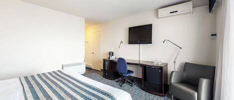 Une chambre d’hôtel équipée d’un lit, d’un bureau, d’une chaise, d’une télévision et d’un appareil de climatisation.