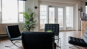 Un vestíbulo de hotel con una planta en maceta grande, dos sillones de cuero negro, una mesa de vidrio y una chimenea.