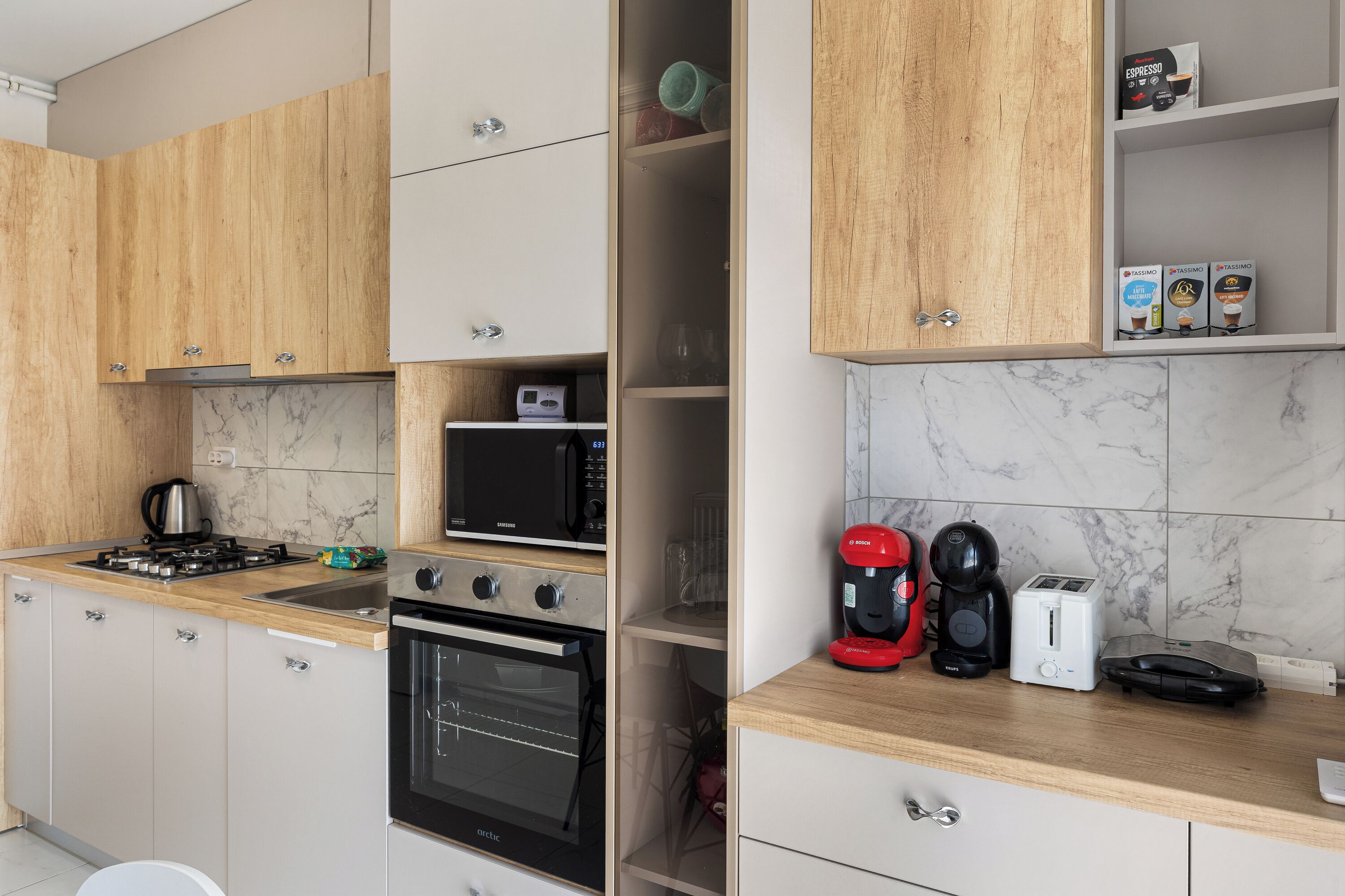 A modern kitchen with wooden cabinets, a built-in microwave, a stove, and various appliances including a coffee maker and toaster.