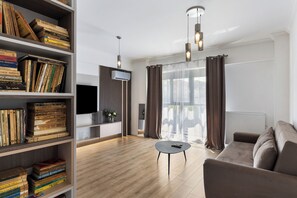 Ein modernes Wohnzimmer mit Holzboden, einer Couch, einem Couchtisch und einem Bücherregal voller Bücher.
