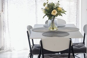 Una mesa de comedor con un jarrón de flores, individuales grises y sillas con acolchado gris.