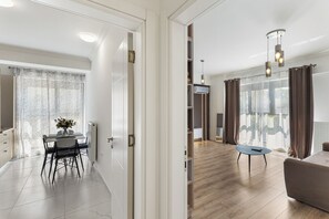 Una sala de estar moderna con un sofá, una zona de comedor con mesa y sillas, y una cocina con un radiador.