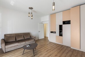 Ein modernes Wohnzimmer mit einer Couch, einem Couchtisch und einer integrierten Küchenzeile mit Schränken.