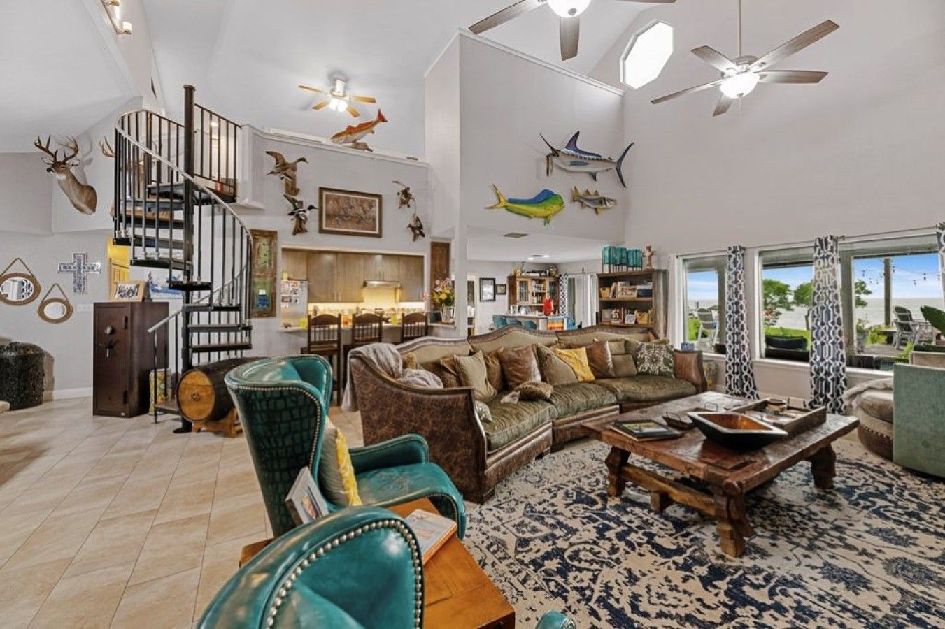 Un salon spacieux avec un grand canapé, une table basse et une cheminée. Un escalier avec une rampe mène à un niveau supérieur.