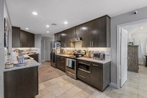 A modern kitchen with dark cabinetry, stainless steel appliances, and a tiled backsplash. - Bayfront 3/2/Loft with pool on Copano Bay with pier (Rockport)