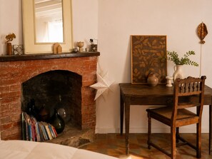 Una habitación acogedora con una chimenea de ladrillo, una mesa de madera con una silla y un adorno en la pared.