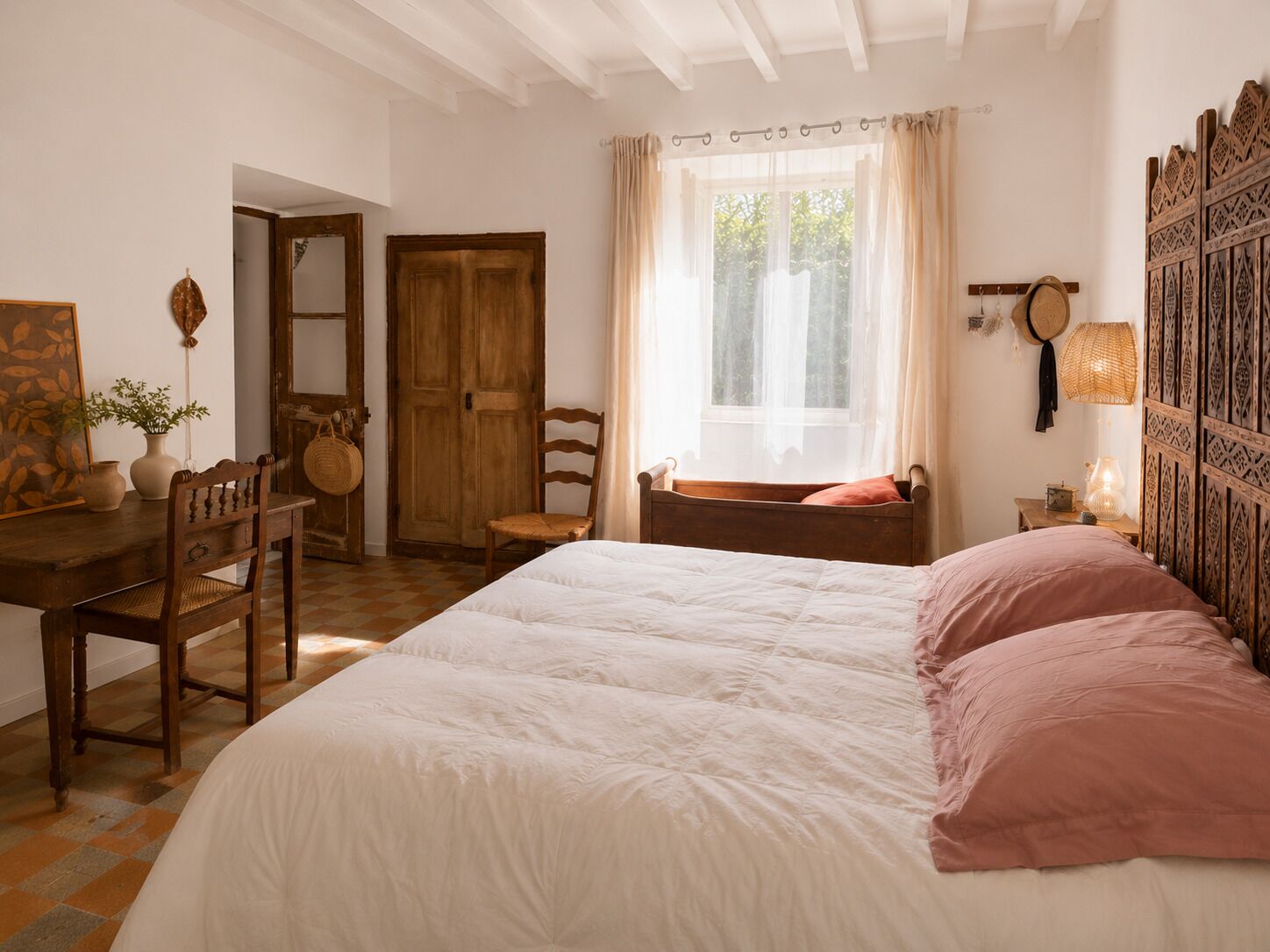 Un dormitorio con una cama grande, muebles de madera, un ventanal con cortinas y una pared con paneles decorativos.