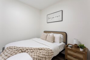A bedroom with a bed, bedside tables, a bedside lamp, a framed quote on the wall, and a blanket. - The Panda Lakehouse - Charming 4 Bedroom Cabin in Lake Hartwell near Clemson (Westminster)