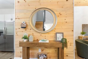 Eine moderne Küche mit einer Holzvertäfelung, einem runden Spiegel und einem kleinen Tisch mit Dekoration.