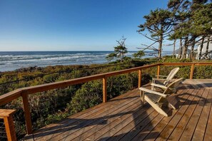 Une terrasse en bois avec une balustrade donnant sur une vue panoramique de la côte.