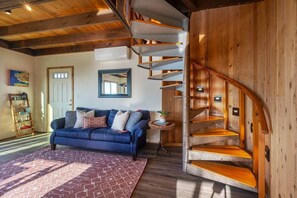 A modern living room with a blue sofa, a wooden staircase, and a bookshelf. - Solitude in Seal Rock (Seal Rock)