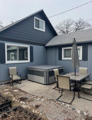 Ein Haus mit einer Terrasse, die einen Tisch, Stühle und eine überdachte Sitzgelegenheit bietet.