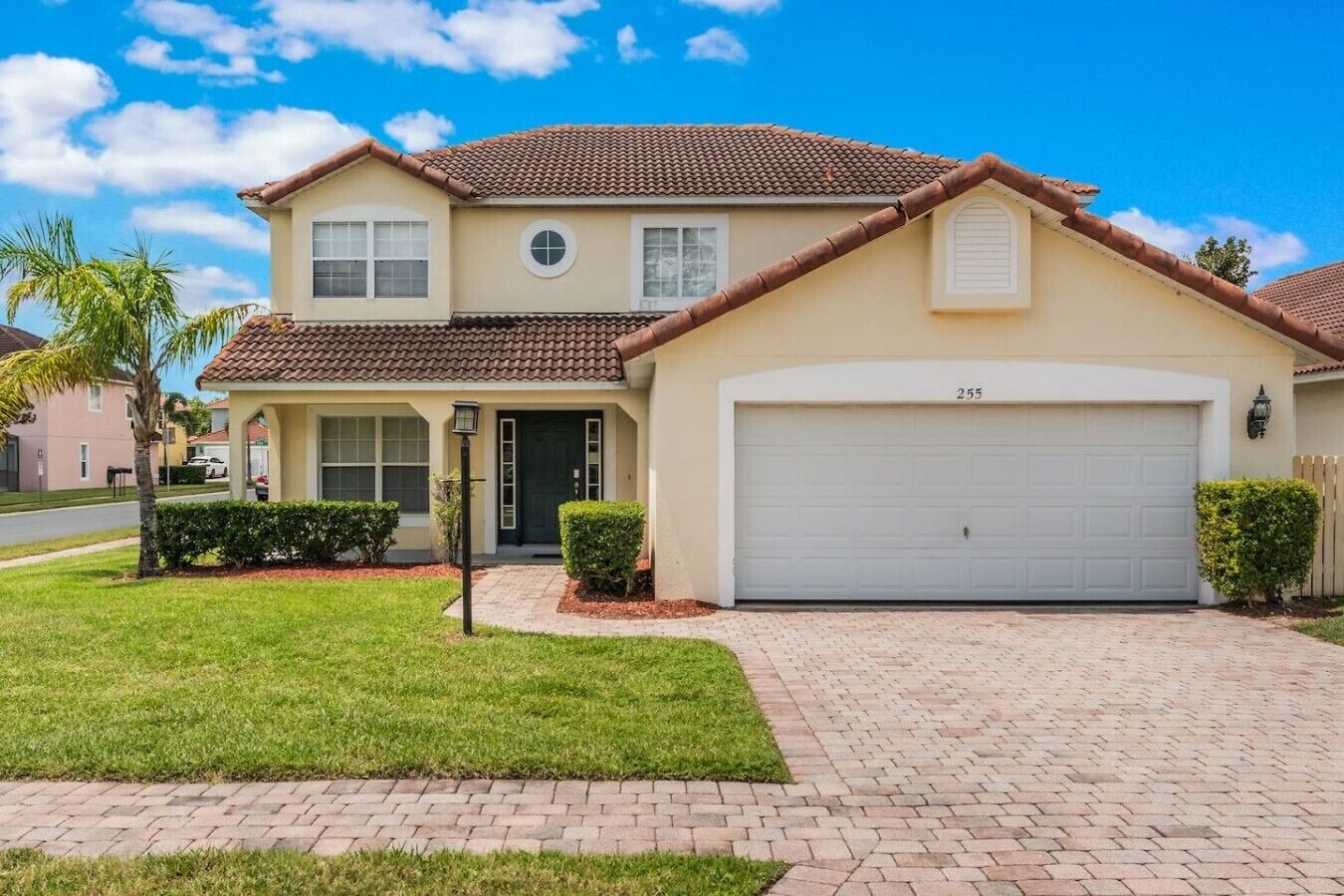 A two-story house with a garage, a front lawn, and a clear sky.