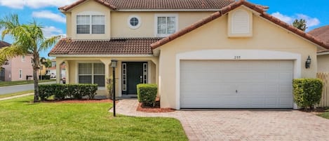 A two-story house with a garage, a front lawn, and a clear sky.