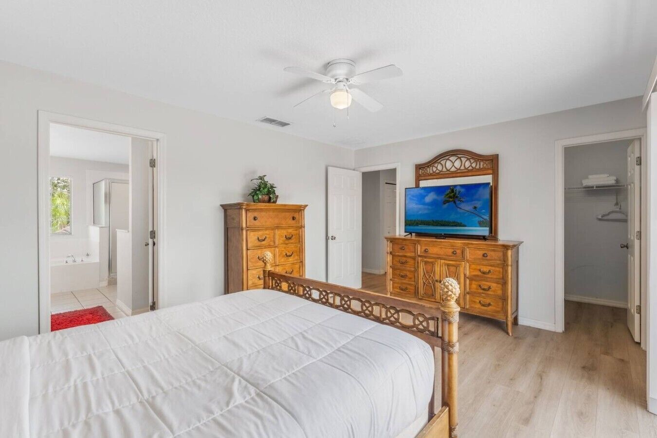 Ein Schlafzimmer mit einem Bett, einem Holzschrank, einem Fernseher und einem Deckenventilator.