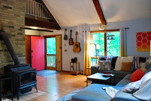 Un salon chaleureux avec une cheminée, un canapé, une table basse et un mur décoré de guitares.