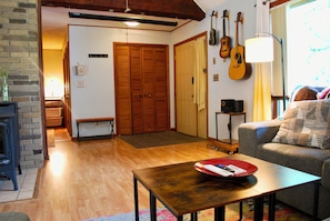 A living room with a wooden floor, a sofa, a coffee table, and a door with louvered shutters.