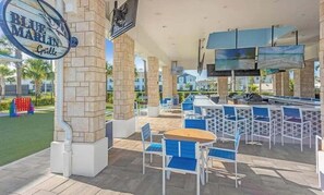 Un espace extérieur aménagé en terrasse, avec une table de billard, des sièges et un panneau indiquant « Blue Marlin Grill ».