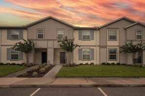A two-story residential building with a symmetrical facade, a central entrance, and a small front yard with landscaping. - Themed 5BR Near Disney - Private Heated Pool & Mario Arcade (Davenport)
