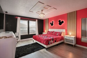 Une chambre à coucher comprenant un lit, un bureau, une chaise, une fenêtre avec des stores, un lustre et des éléments de décoration murale.