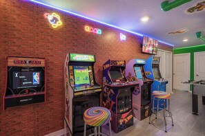 A room with arcade games, a foosball table, and a TV screen. - Themed 5BR Near Disney - Private Heated Pool & Mario Arcade (Davenport)