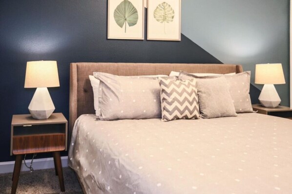 A bedroom with a bed, two nightstands, two lamps, and two framed leaf artworks on the wall. - Themed Championsgate private pool water park BBQ (Kissimmee)