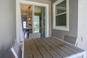 A dining area with a wooden table and chairs, a sliding glass door leading to a kitchen, and a window with blinds. - Themed Championsgate private pool water park BBQ (Kissimmee)