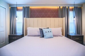 Ein Bett mit Kopfstütze, zwei Nachttische und eine Wand mit geometrischem Muster.