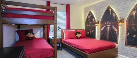 A room with bunk beds, a desk, and a wall with arched windows.