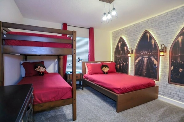 Ein Zimmer mit Etagenbetten, einem Schreibtisch und einer Wand mit Rundbogenfenstern.