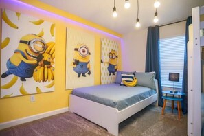 Una camera da letto con un letto, un tavolino e decorazioni murali con personaggi dei cartoni animati.