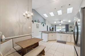 A modern kitchen with a built-in island, pendant lighting, and a stainless steel refrigerator. - Disney Luxury Escape Private Pool 4BR BBQ (Kissimmee)