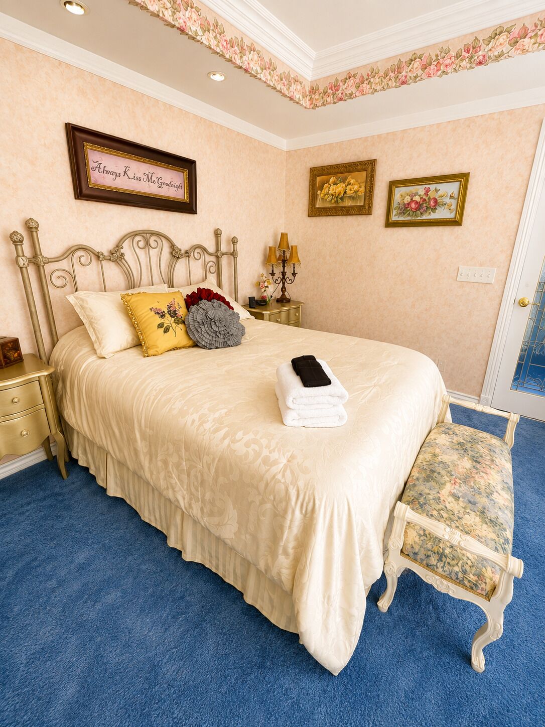 Quarto com cama, mesas de cabeceira, um banco e decorações nas paredes.