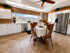 A modern kitchen with a dining area, featuring a view of mountains, a ceiling fan, and stainless steel appliances.