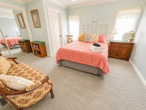 A bedroom with a bed, a chair, a dresser, and a mirror.