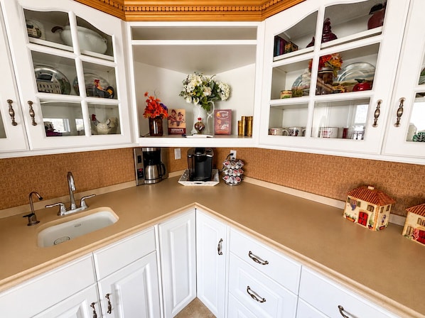 A kitchen with white cabinets, a sink, a coffee maker, and decorative items.
