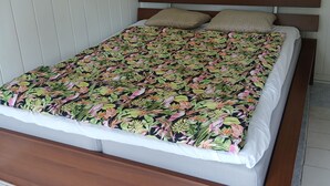 Una cama con colcha estampada, cabecera de madera y dos almohadas.
