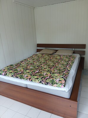 Un lit avec une couvre-lit à motifs floraux, une tête de lit en bois et deux oreillers.