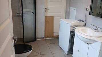 A bathroom with a toilet, a shower, a sink, and a mirror.