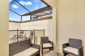 A sunlit patio with wicker furniture and a glass ceiling. - Luxury 5 Bdrm Championsgate Pool, Water Park, Bbq (Davenport)