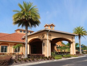 A building with a covered entrance, palm trees, and a clear sky. - Bella Blue at Bella Vida Resort (Kissimmee)