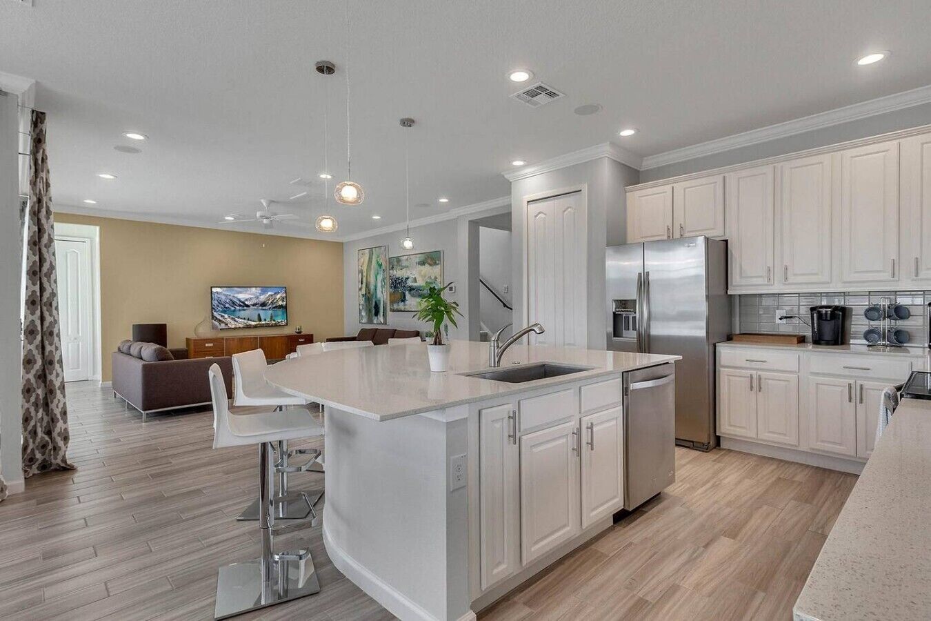 A modern kitchen with white cabinetry, a central island, and a dining area with a sofa and chairs.