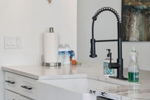 A kitchen with a modern faucet, a marble countertop, and a white cabinet. - Luxury Coastal Haven, Pool, Beach, Golf and Relax (Palm Coast)