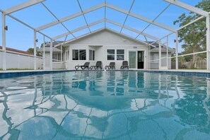 A swimming pool with a covered area and lounge chairs. - Luxury Coastal Haven, Pool, Beach, Golf and Relax (Palm Coast)