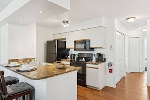 Eine moderne Küche mit Granit Arbeitsplatten, Edelstahlgeräten und weißen Schränken.