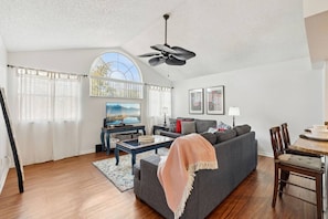 Ein Wohnzimmer mit Sofa, Couchtisch, Fernseher und Deckenventilator.
