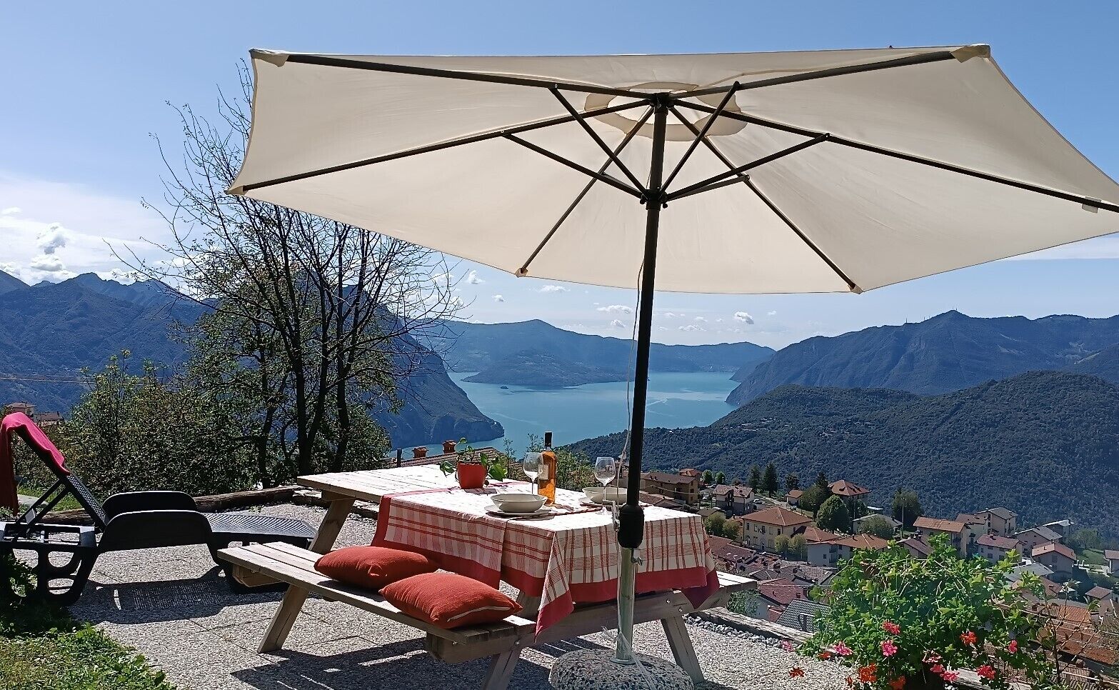 Uma área de refeições ao ar livre com mesa, cadeiras, um guarda-sol e vista para a montanha.