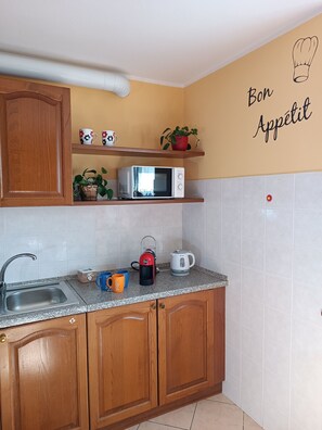 Een keuken met houten kastjes, een magnetron, waterkoker en koffiezetapparaat.